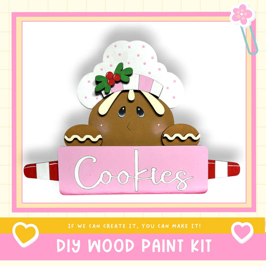 A wooden gingerbread man figure holding a sign that says "Cookies" in a pink background.