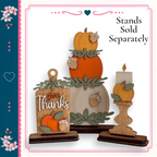 a set of wooden ornaments, including a carved pumpkin, a candle holder, and a wooden sign with the phrase "give thanks". The ornaments are arranged in a festive manner, suggesting they are intended for use during the Thanksgiving holiday season.