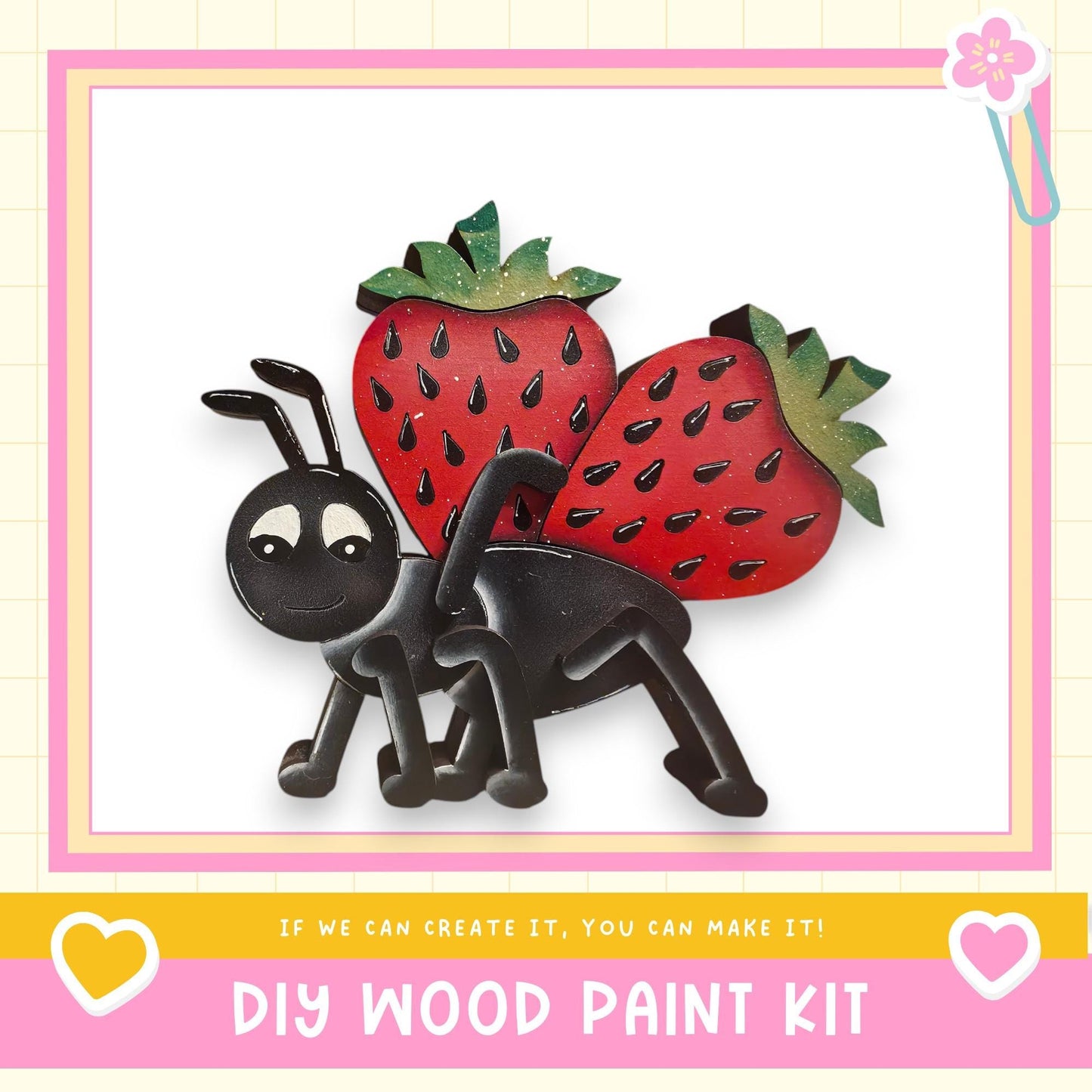 The image is a DIY wood paint kit featuring a black ant with red strawberries on its back, set against a pink and yellow background.