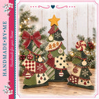 A handmade Christmas tree set with various ornaments and decorations, including a star, bows, and snowflakes, placed on a wooden surface against a backdrop of greenery and twinkling lights.