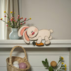 a shelf with a decorative Easter bunny figure, a vase of flowers, a woven basket, and some Easter eggs.