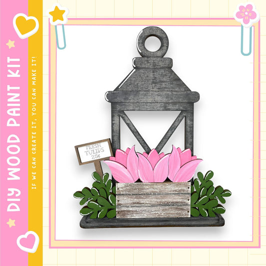 A wooden lantern with pink tulips in a wooden planter box, set against a white background with a pink and yellow border.