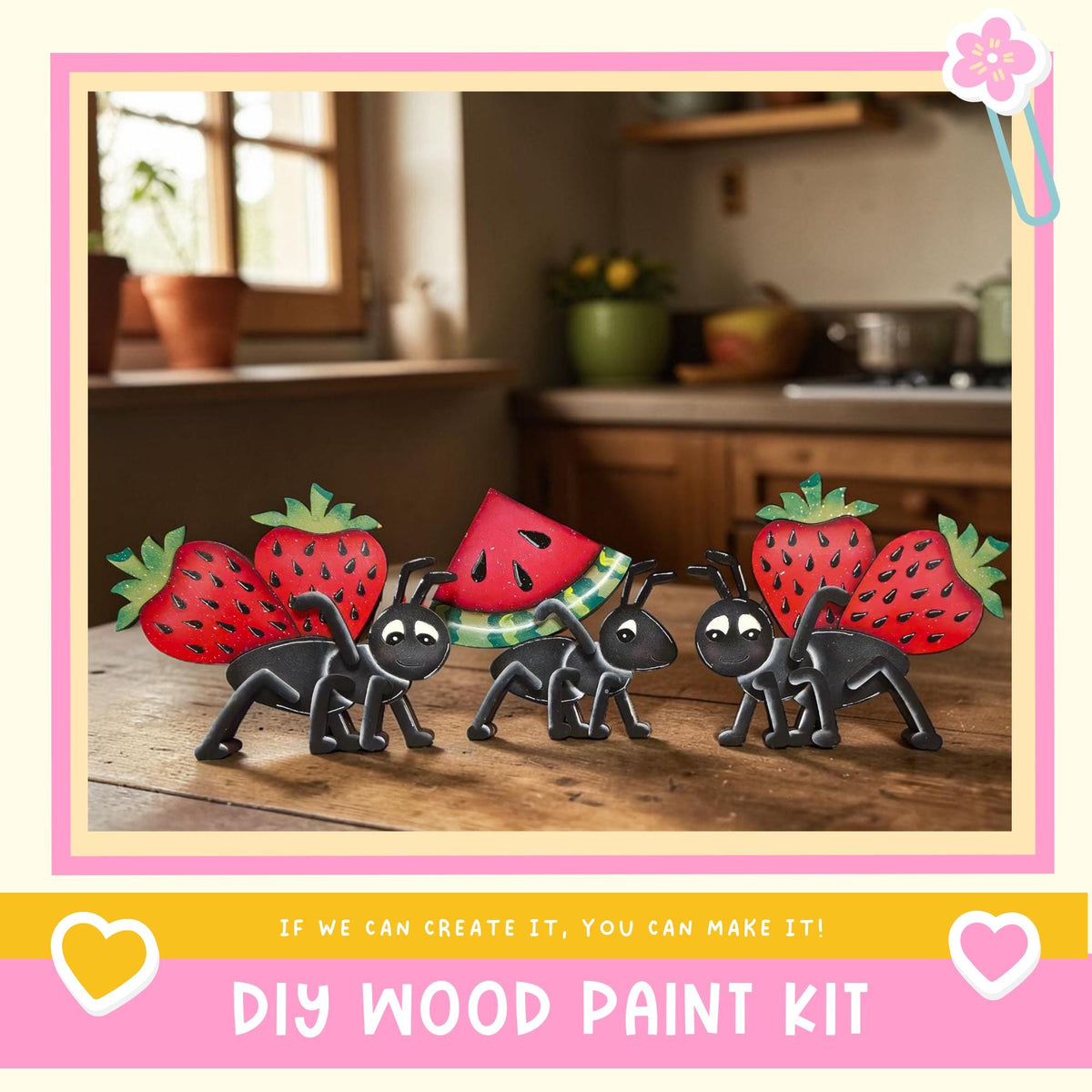 A DIY wood paint kit featuring a whimsical scene of four black ants carrying a watermelon on a wooden surface, with a kitchen counter and potted plant in the background.