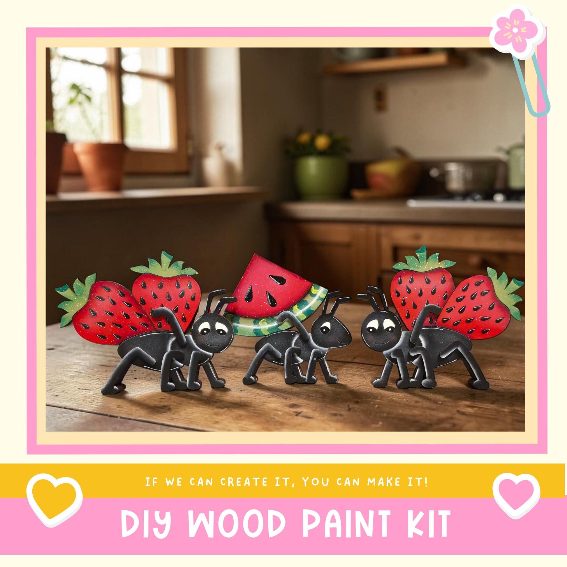 A DIY wood paint kit featuring a whimsical scene of four black ants carrying a watermelon on a wooden surface, with a kitchen counter and potted plant in the background.