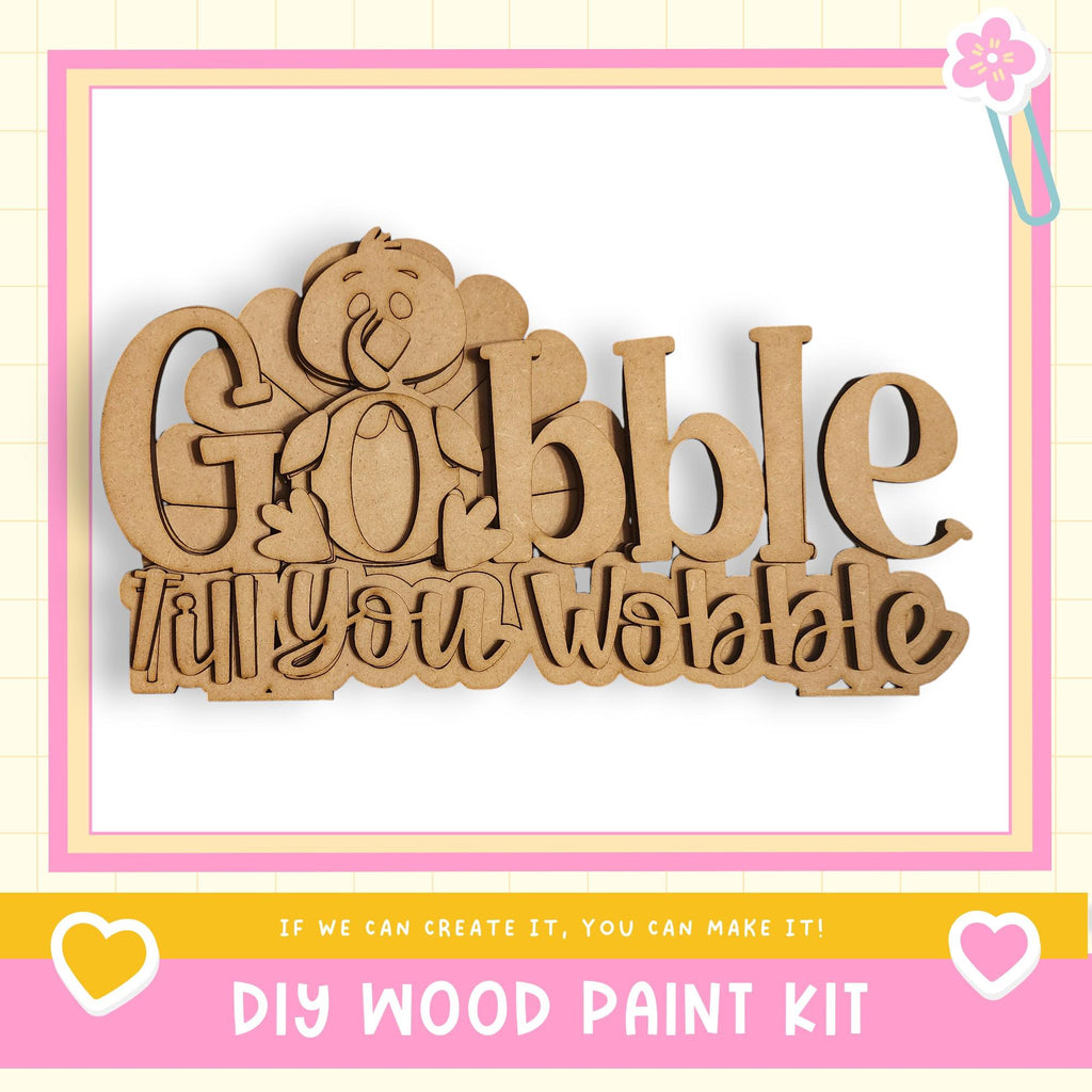 a DIY wood paint kit with a wooden sign that says "Gobble till you wobble" in a playful font.
