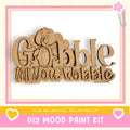a DIY wood paint kit with a wooden sign that says "Gobble till you wobble" in a playful font.