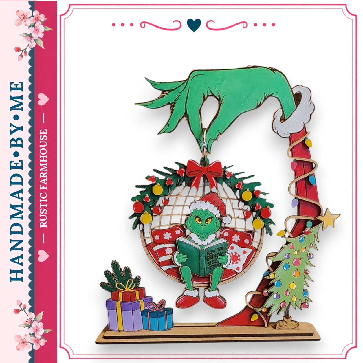 A hand-made ornament featuring a green Grinch-like character reading a book, surrounded by Christmas decorations such as a wreath, presents, and a Christmas tree.