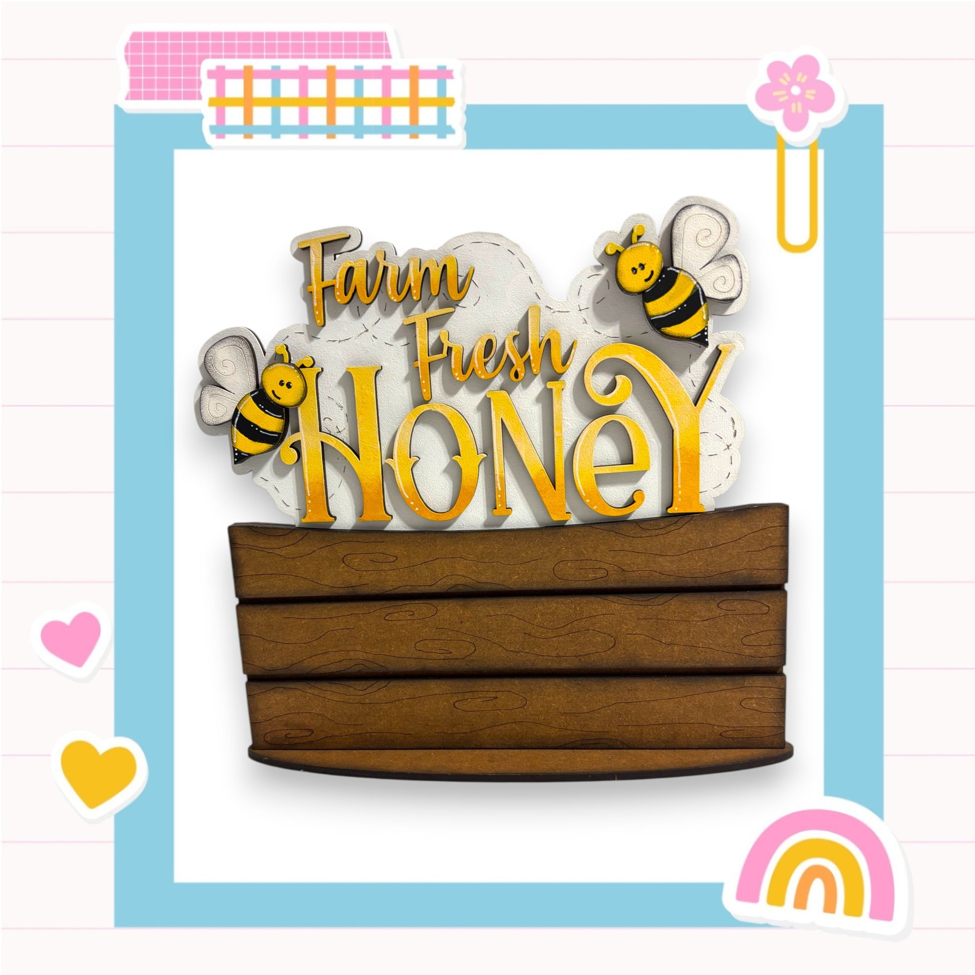 a wooden box with the words "Farm Fresh Honey" written on it, along with two cartoon bees. The background is a light blue color with a pink and white checkered pattern.