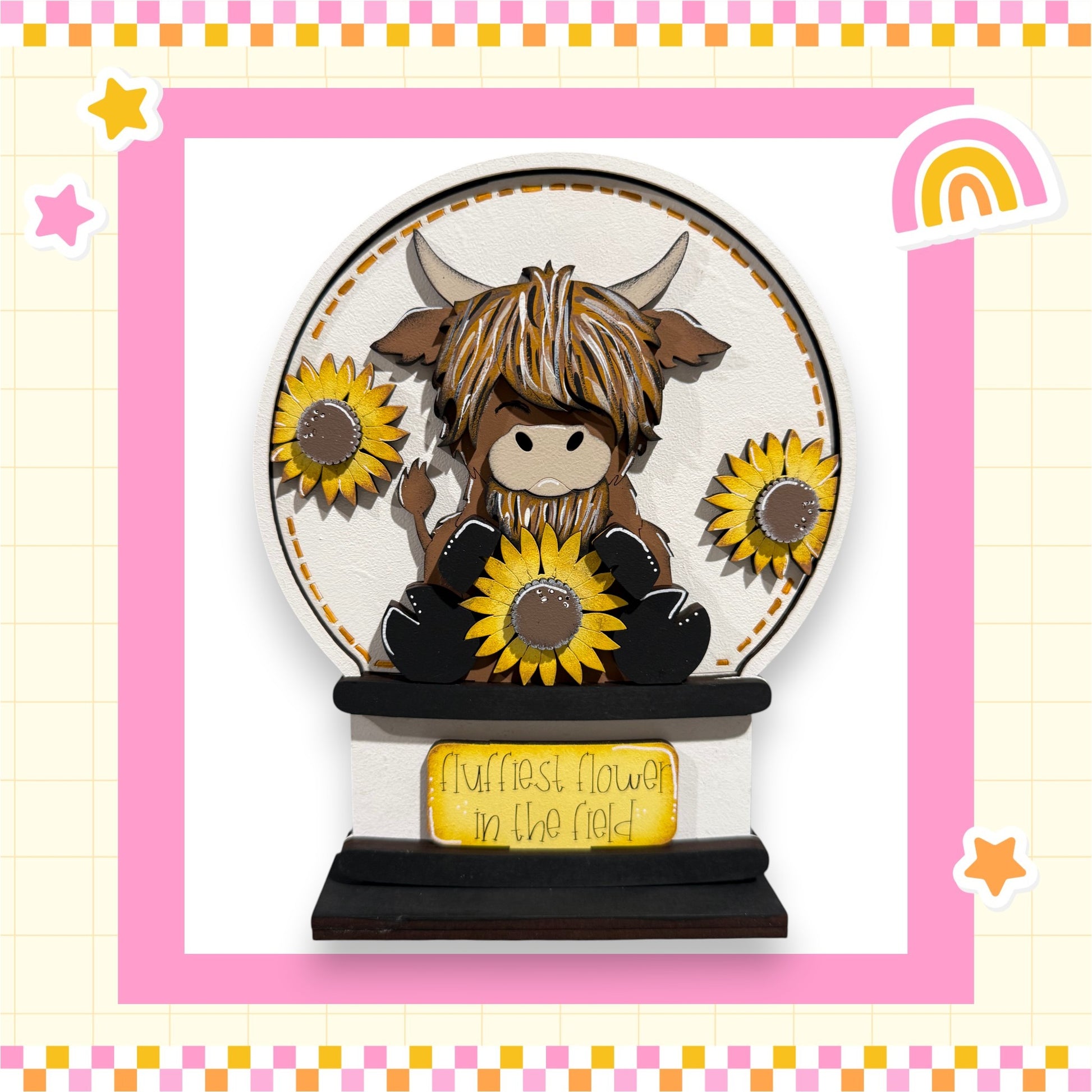 A wooden snow globe containing a cartoon cow with horns and a flower, surrounded by sunflowers.