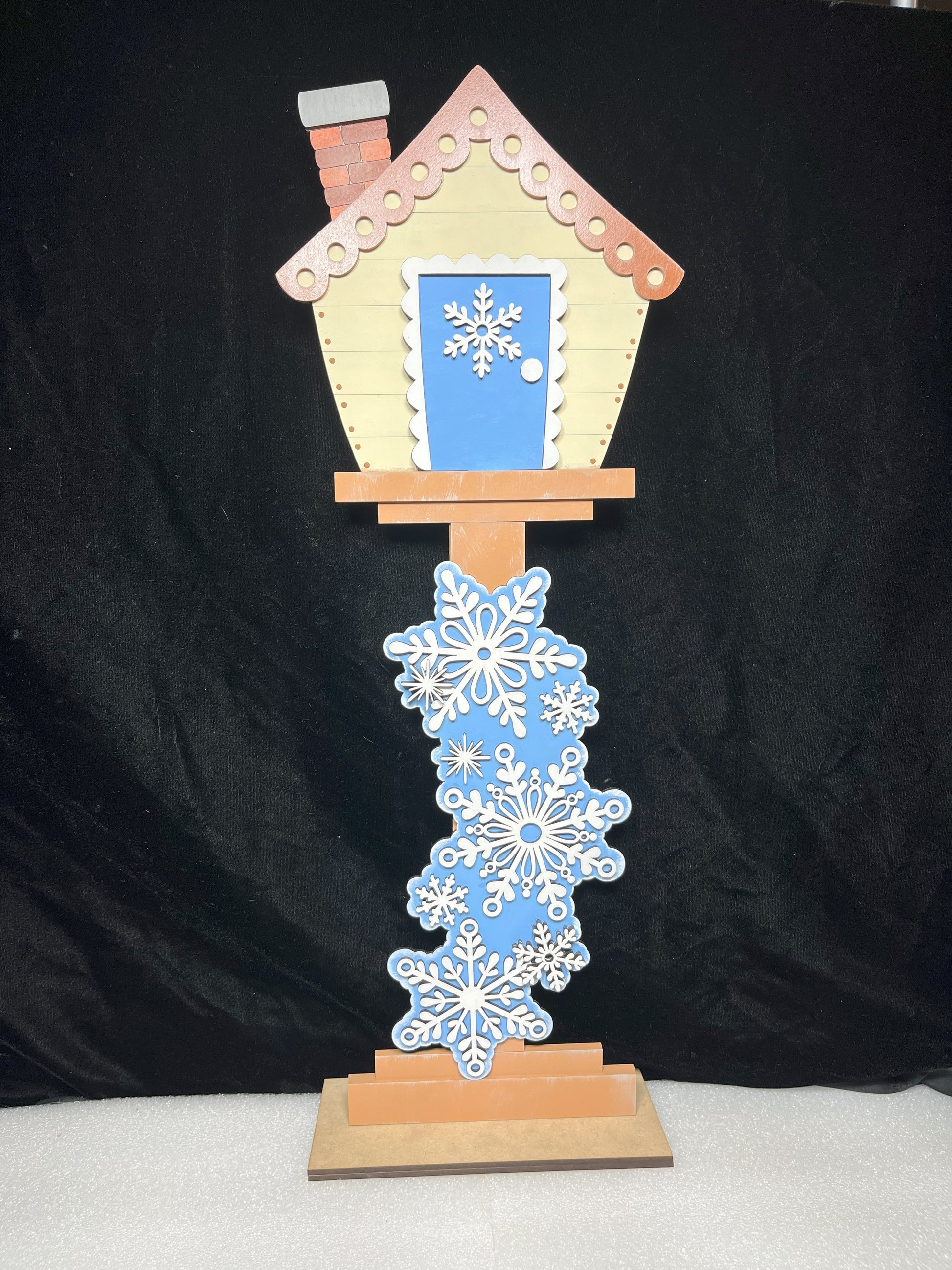 a birdhouse with snowflakes on it on a stand