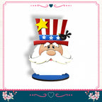 A cartoon-style Santa Claus figure wearing a patriotic hat with stars and stripes, a yellow star, and a black bird, set against a white background with a pink border and floral decorations.