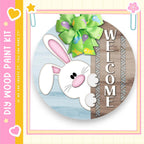 a round wooden sign with a cartoon rabbit and a green bow, along with the word "WELCOME" written on it.
