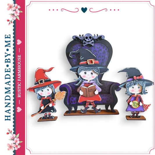 A hand-made wooden dollhouse featuring three cartoon-style dolls dressed as witches, with one sitting on a chair and the other two standing nearby.