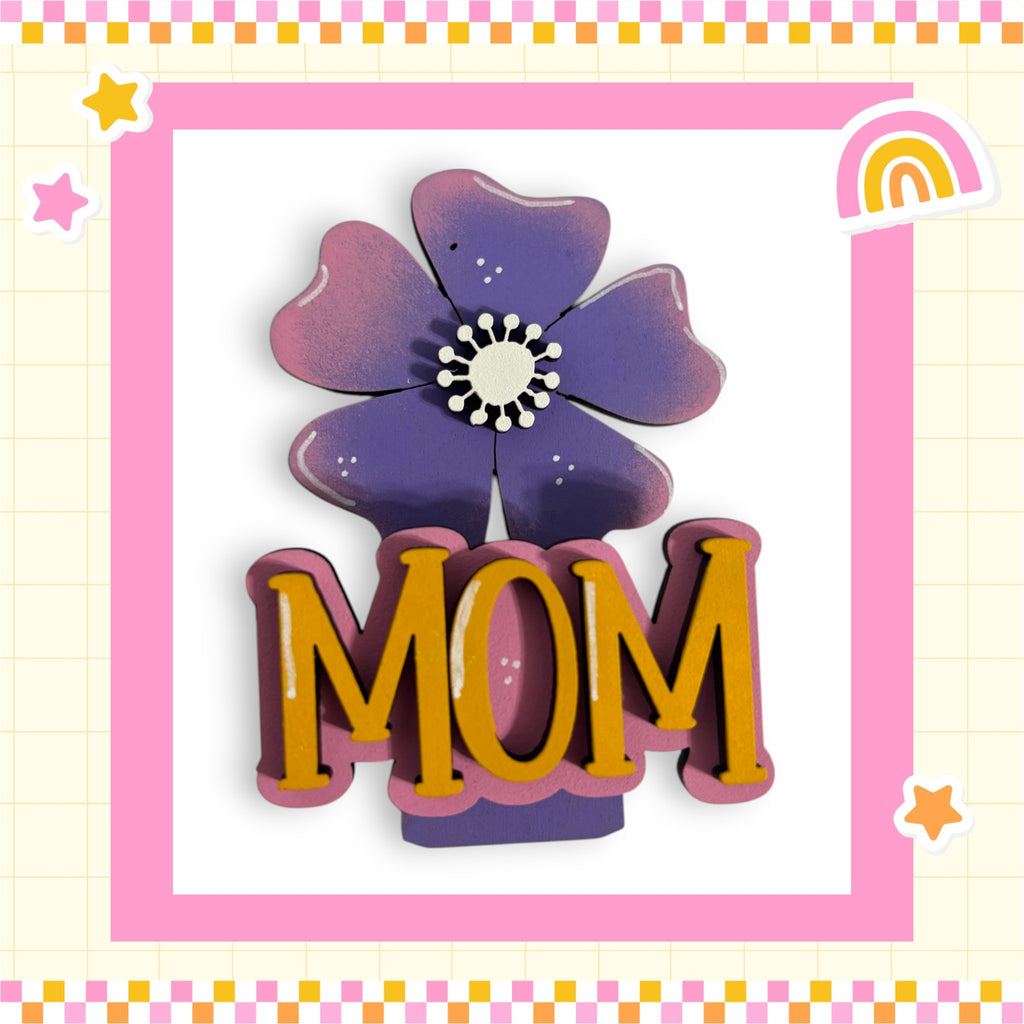 A decorative floral design with the word "MOM" prominently displayed in the center, surrounded by a pink and yellow border.