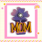 A decorative floral design with the word "MOM" prominently displayed in the center, surrounded by a pink and yellow border.