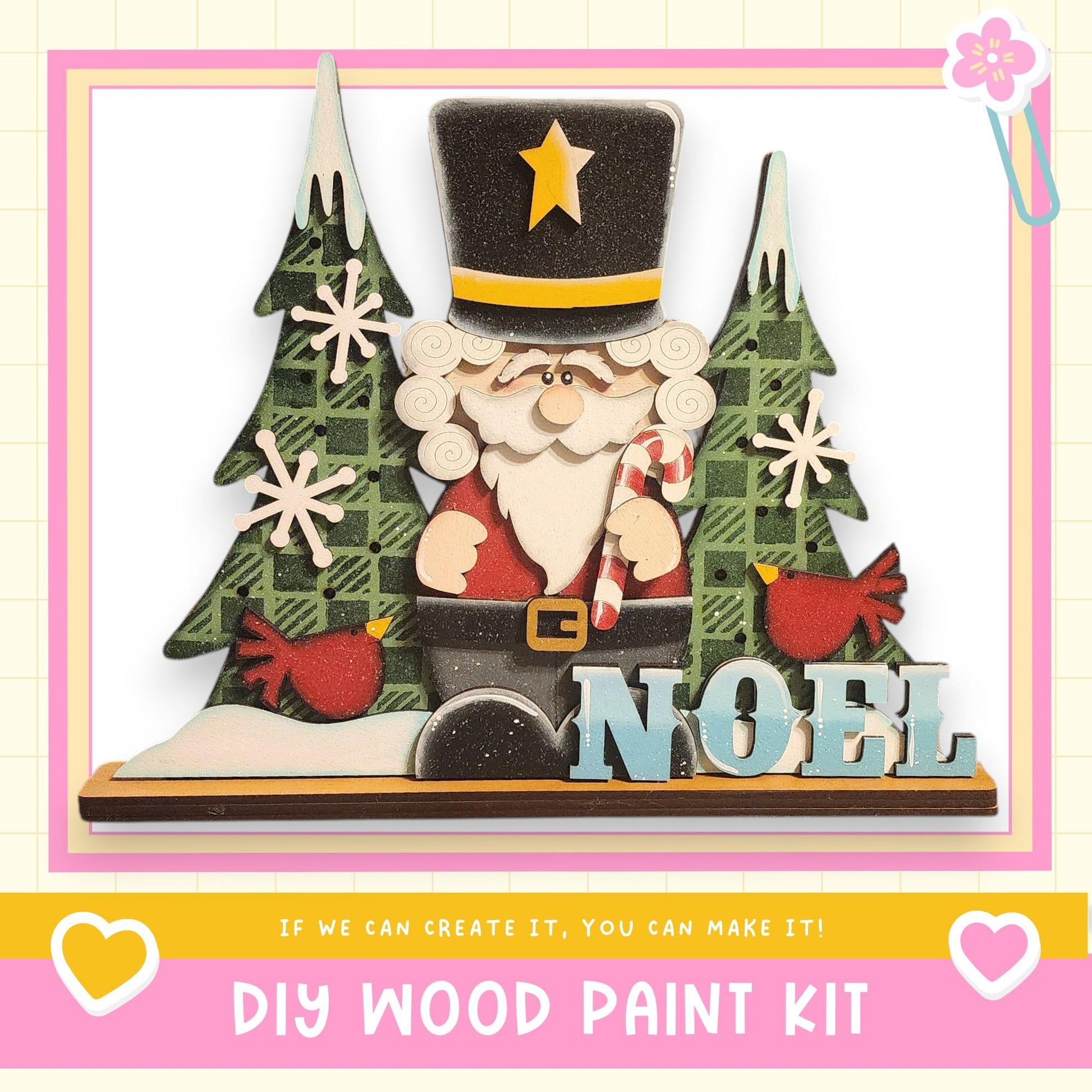 A DIY wood paint kit featuring a wooden Santa Claus figure surrounded by Christmas trees, snowflakes, and the word "Noel" written on it.