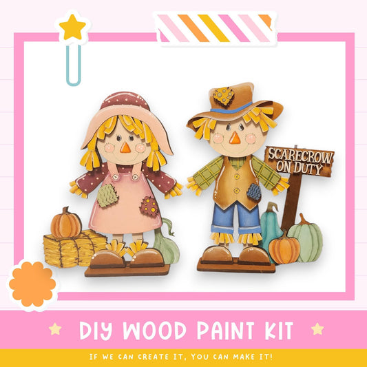 two wooden scarecrow figures, one wearing a pink dress and the other wearing a green dress, standing next to a sign that says "SCAREcrow on Duty". The image also includes a text box that reads "DIY WOOD PAINT KIT" and a star icon, suggesting that the image is part of a larger collection or series.