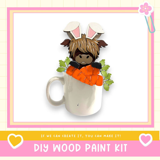 A white mug with a cartoon character wearing a pair of bunny ears and holding carrots, set against a pink and white background.