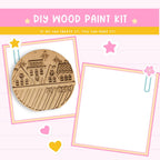 The image is a DIY wood paint kit advertisement, featuring a wooden ornament with a winter scene and a blank white space for painting.