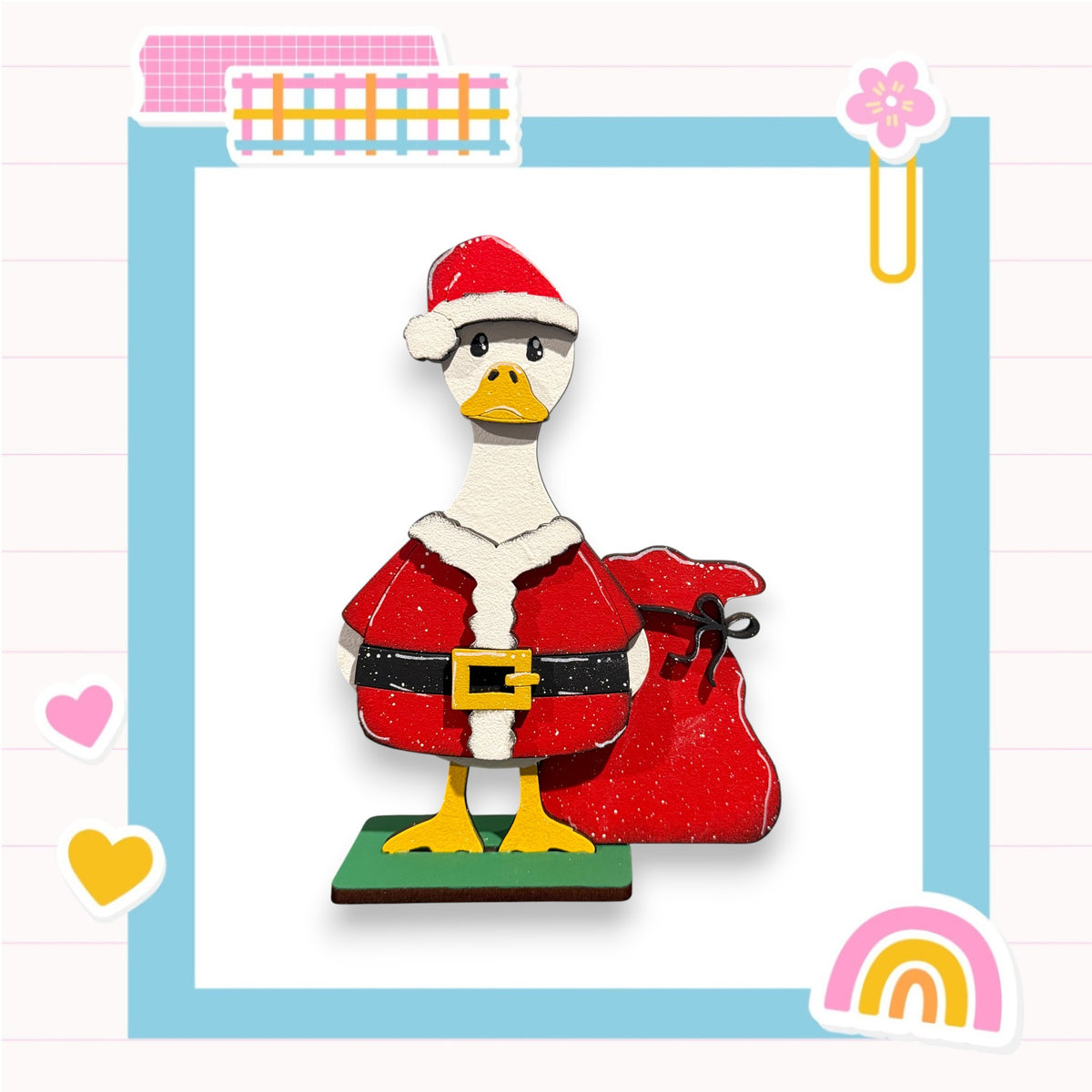 A cartoon duck wearing a Santa Claus outfit and holding a red sack, set against a background with a pink and blue border and various decorative elements.