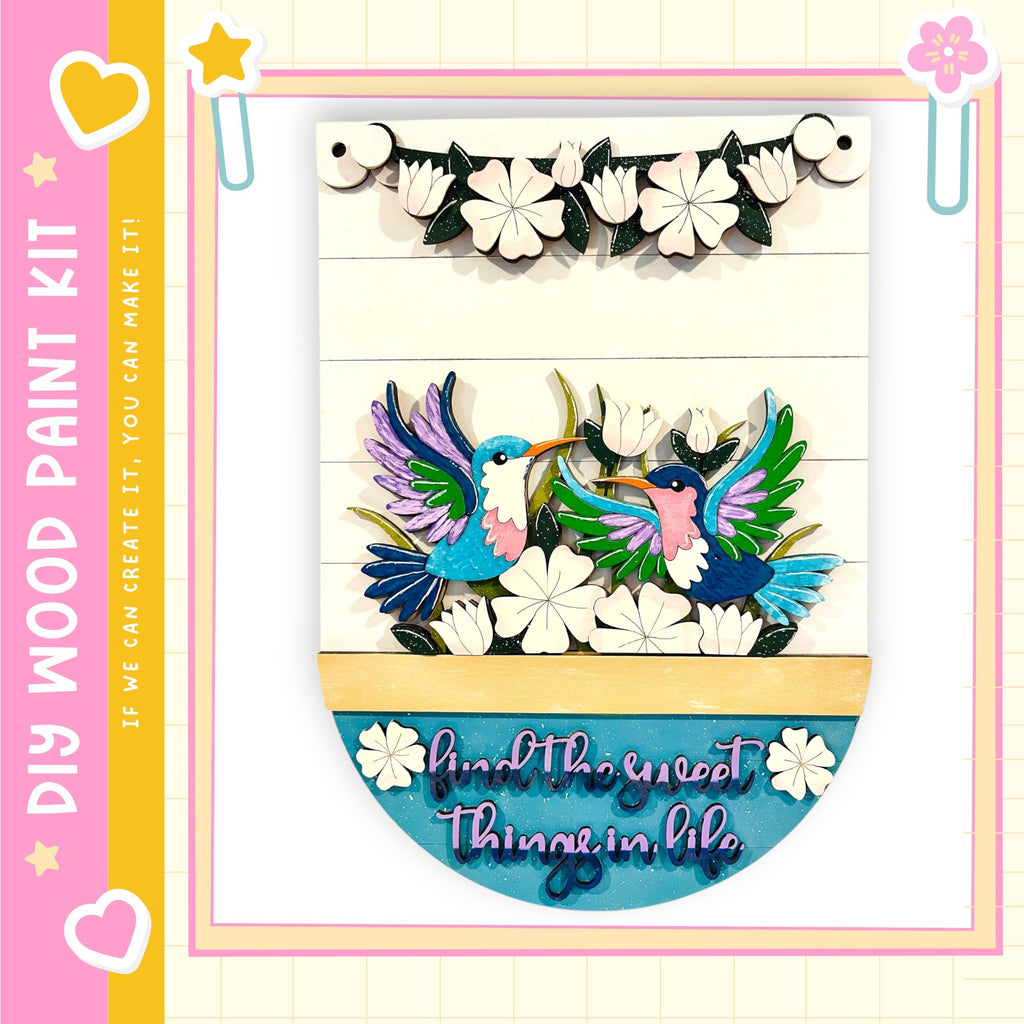The image is a colorful and vibrant painting kit featuring a wooden frame with a decorative border. The frame is adorned with a variety of flowers and birds, creating a lively and cheerful atmosphere. The kit appears to be designed for children, as indicated by the playful and colorful nature of the artwork.