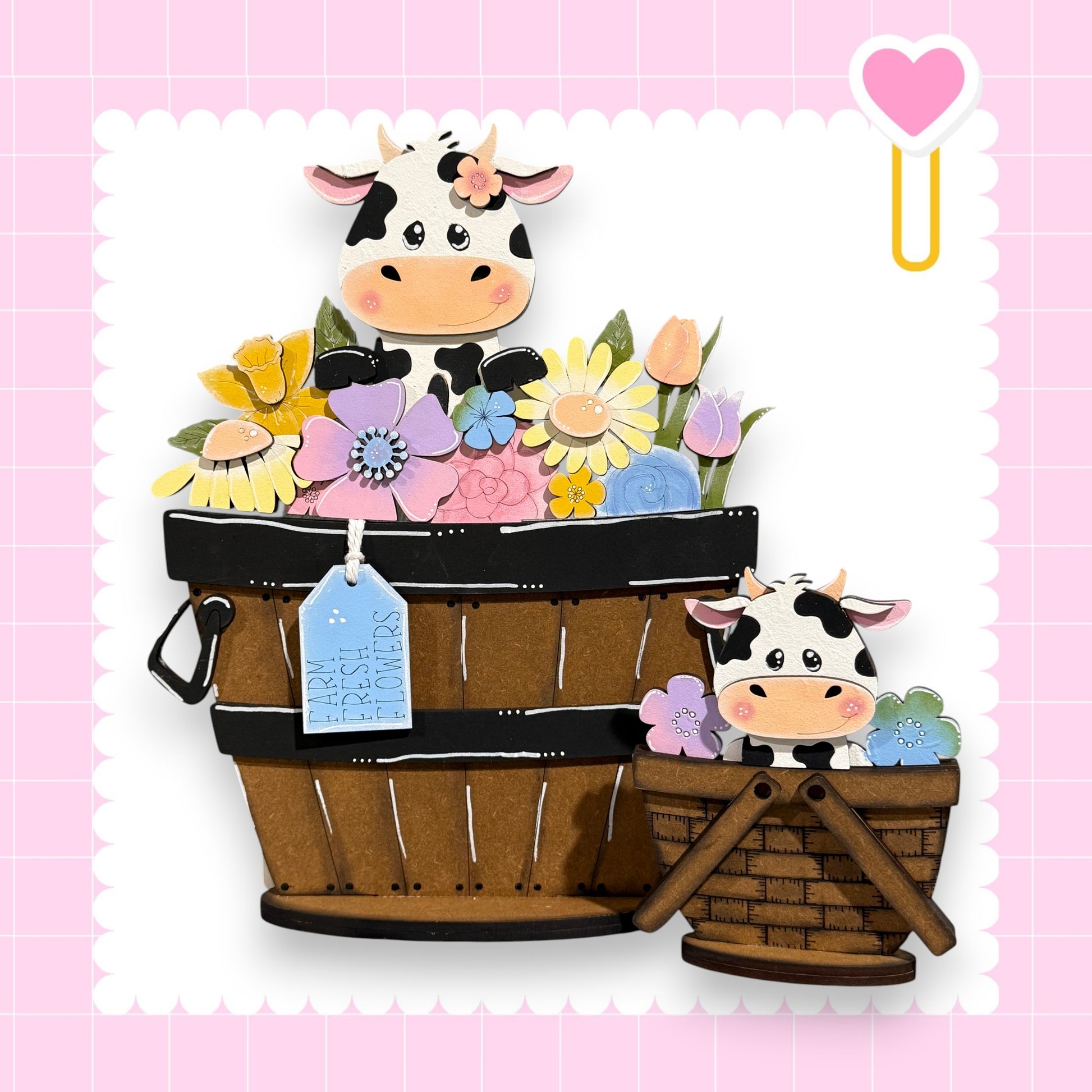 A wooden basket filled with colorful flowers and a smaller wooden basket with a cow inside, set against a pink background with a heart symbol.