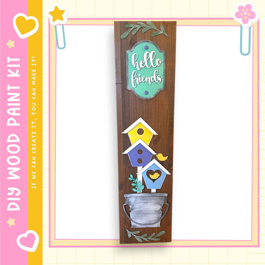 a wooden sign with a birdhouse design and the text "Hello friends" on it. The sign is hanging on a wall, and there is a heart and a star decoration on the left side of the image.