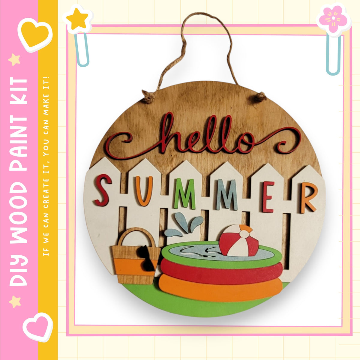 A wooden sign with the word "Hello Summer" written on it, hanging on a fence. The sign also features a beach ball, a bucket, and a star.