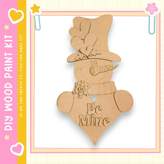 A wooden snowman decoration with a heart-shaped cutout and the text "Be Mine" on its chest.