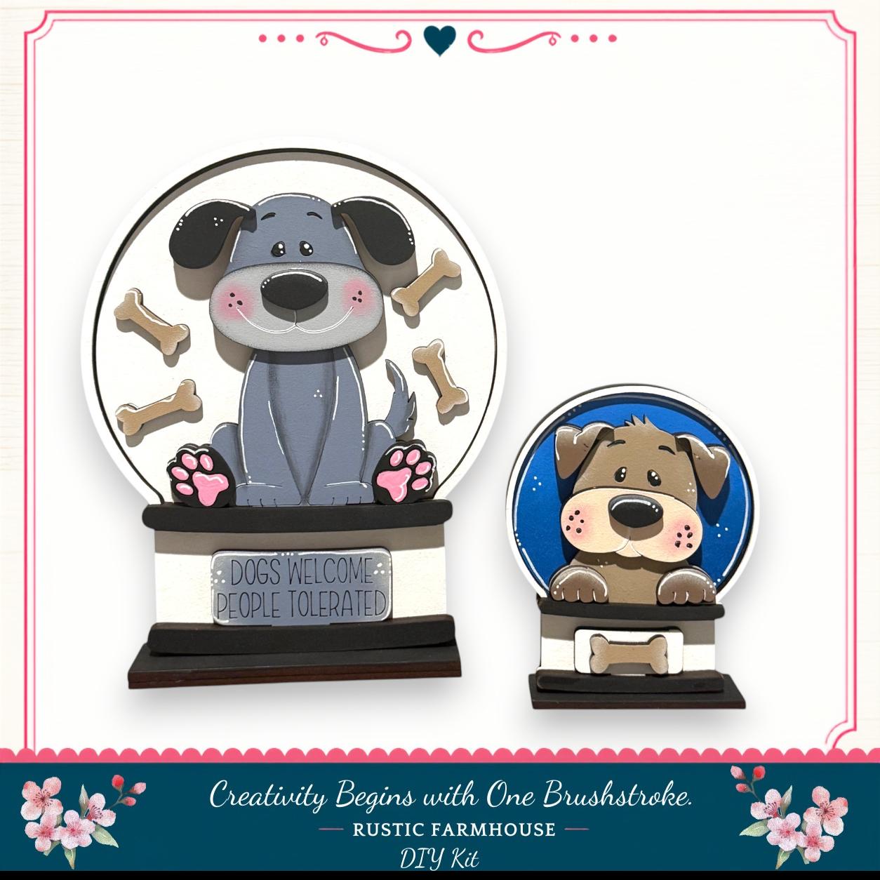 two dog-themed snow globes, one larger and one smaller, both containing a dog and surrounded by dog bones. The larger snow globe has a sign that says "DOGS WELCOME PEOPLE TOLERATED", while the smaller one has a sign that says "DOGS WELCOME PEOPLE TOLERATED". The snow globes are set against a white background, and there is a decorative border around the image.