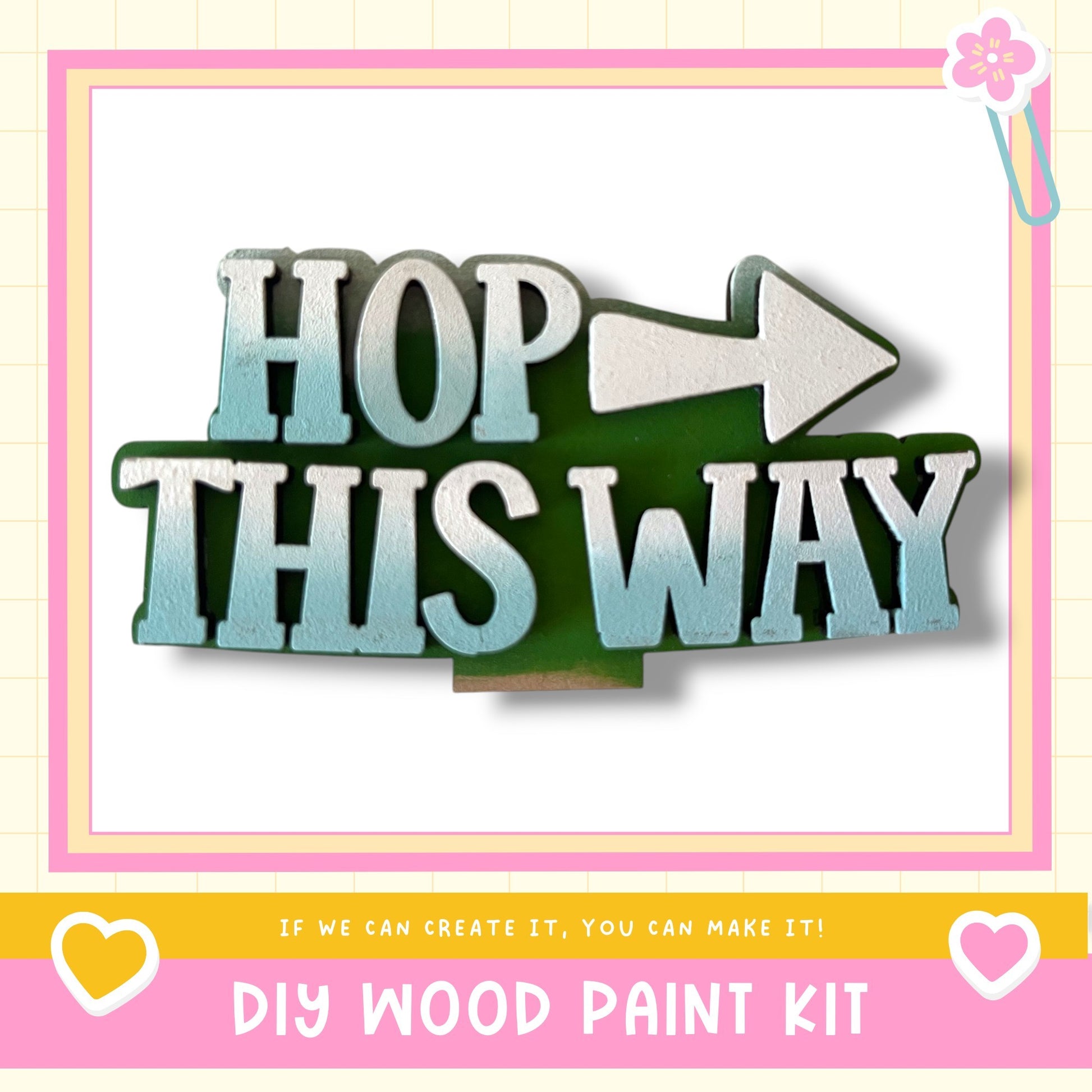 The image is a DIY wood paint kit with a large sign that says "HOP THIS WAY" and a pink and white border.