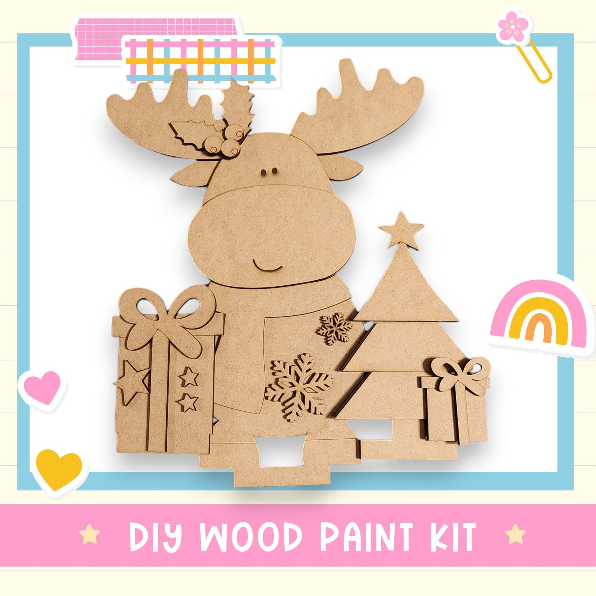 a DIY wood paint kit for creating a wooden Christmas tree decoration. The kit includes a wooden tree, a bow, and a star, all made of cardboard. The kit is presented in a pink and blue frame, with various decorative elements such as hearts and a rainbow.