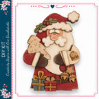A wooden Santa Claus figure holding a Christmas tree and presents, with a "ho ho" tag attached to his hand.
