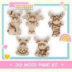 The image is a DIY wood paint kit featuring five wooden animal figurines, including moose, bats, and a pumpkin.