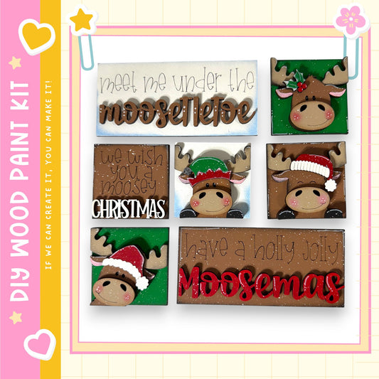 The image is a collage of six wooden Christmas-themed decorations, including moose heads and other festive elements. The decorations are arranged in a grid-like pattern, with each one featuring a different design and color scheme. The text on the decorations includes phrases like "Meet me under the moose", "We wish you a merry Christmas", and "Have a holly jolly Moosemas".