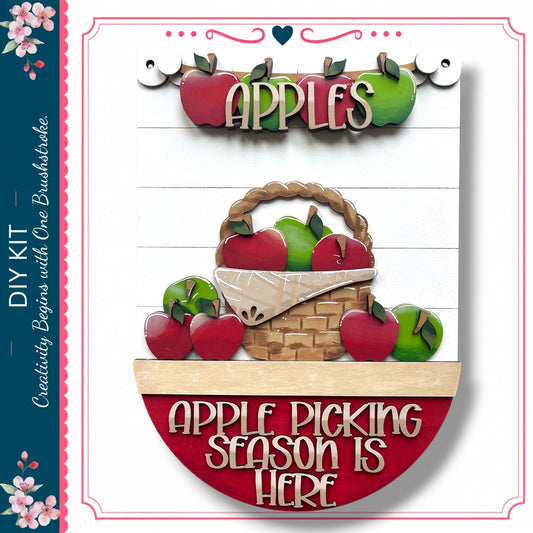 The image is a decorative piece featuring a basket filled with apples, accompanied by the text "APPLES" and "APPLE PICKING SEASON IS HERE".