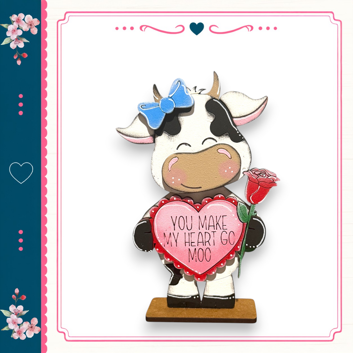 A wooden cow figurine holding a heart-shaped sign that says "You make my heart go moo".