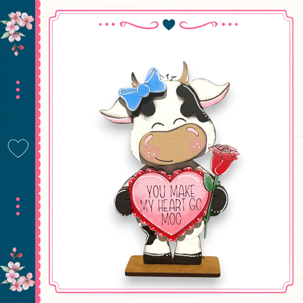 A wooden cow figurine holding a heart-shaped sign that says "You make my heart go moo".