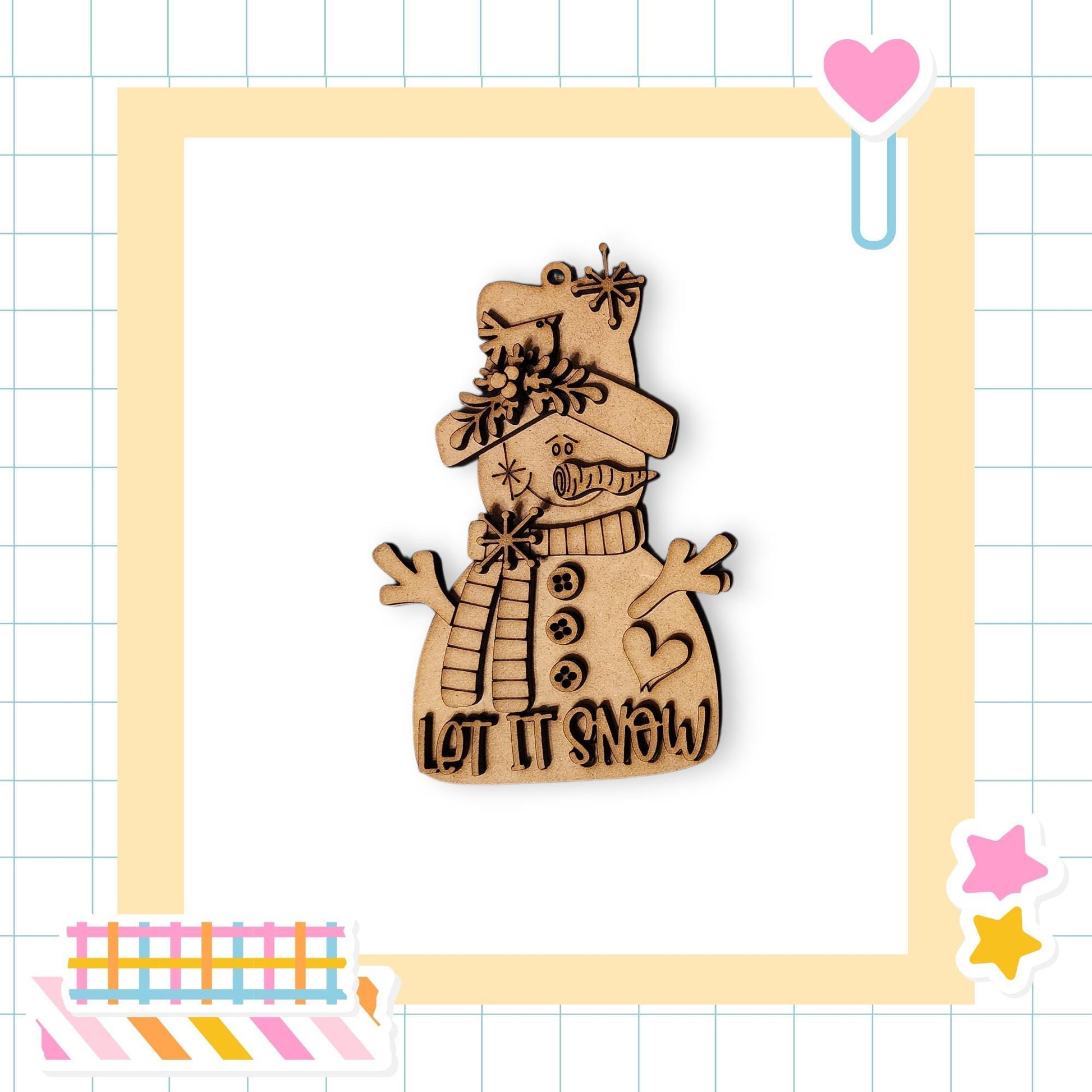 A wooden snowman ornament with the text "LET IT SNOW" on it, set against a white background with a grid pattern.