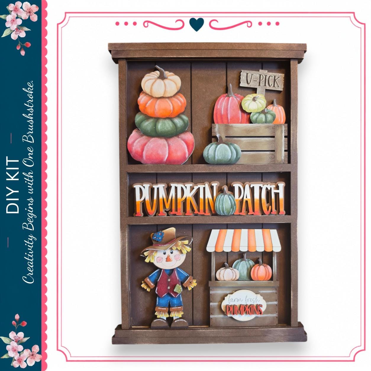 The image is a wooden display with various fall decorations, including pumpkins, a scarecrow, and a sign that says "V-PICK". The display appears to be a creative DIY project, possibly for a pumpkin patch or fall-themed room.
