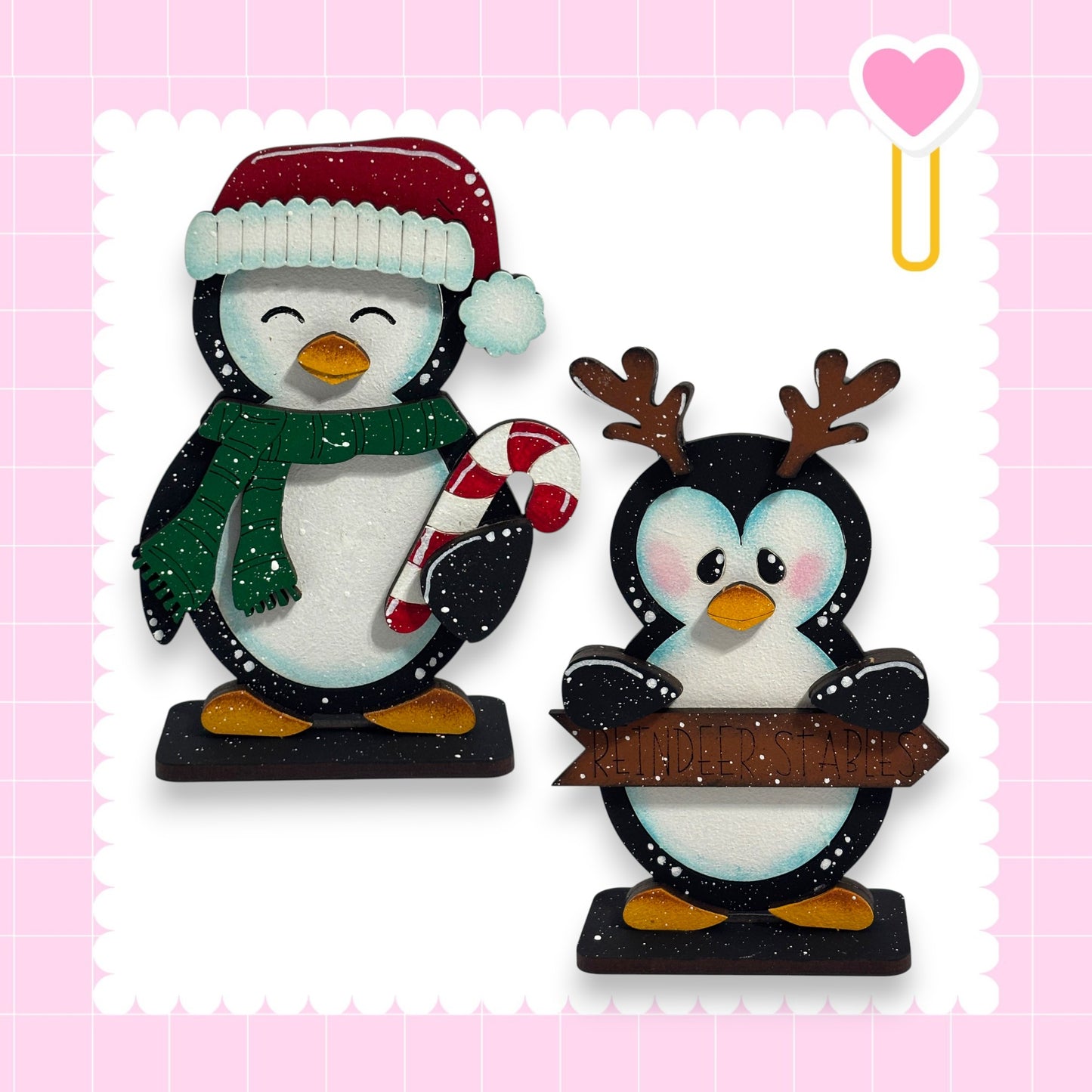 two cute penguin figurines, one wearing a Santa hat and the other holding a sign.