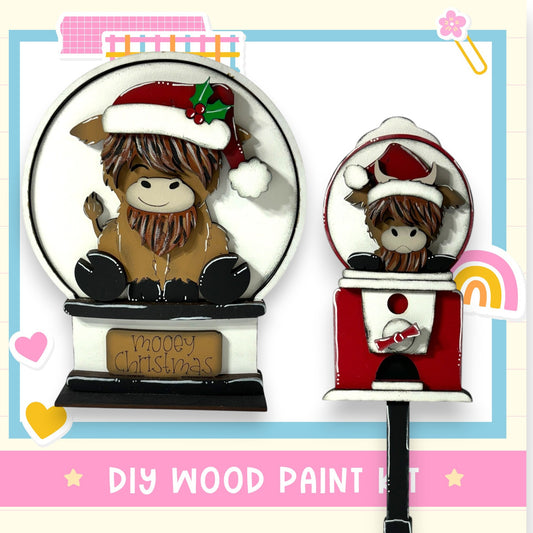 a wooden snow globe with a small cow figurine inside, along with a sign that says "Mooey Christmas". The snow globe is decorated with a Santa hat and a bow, and the sign inside the snow globe wishes "Mooey Christmas". The background of the image is a pink and blue color scheme with various decorative elements.