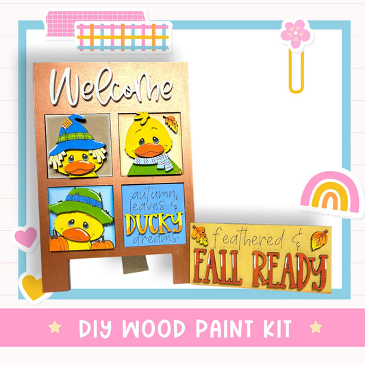 The image is a colorful welcome sign featuring cartoon duck faces and autumn leaves, along with a DIY wood paint kit labeled "FALL READY".