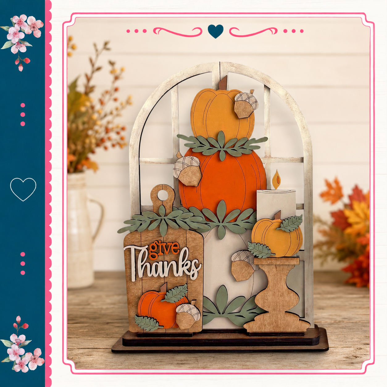A wooden display with a carved pumpkin and acorns, featuring the text "Give Thanks" in a decorative font. The display is set against a backdrop of autumn foliage and flowers, creating a festive and seasonal atmosphere.