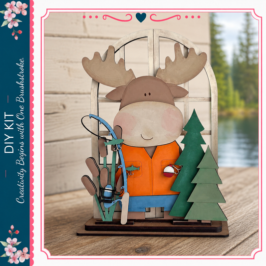 A wooden toy moose holding fishing gear, including a fishing rod and a small fish, is displayed on a wooden surface.
