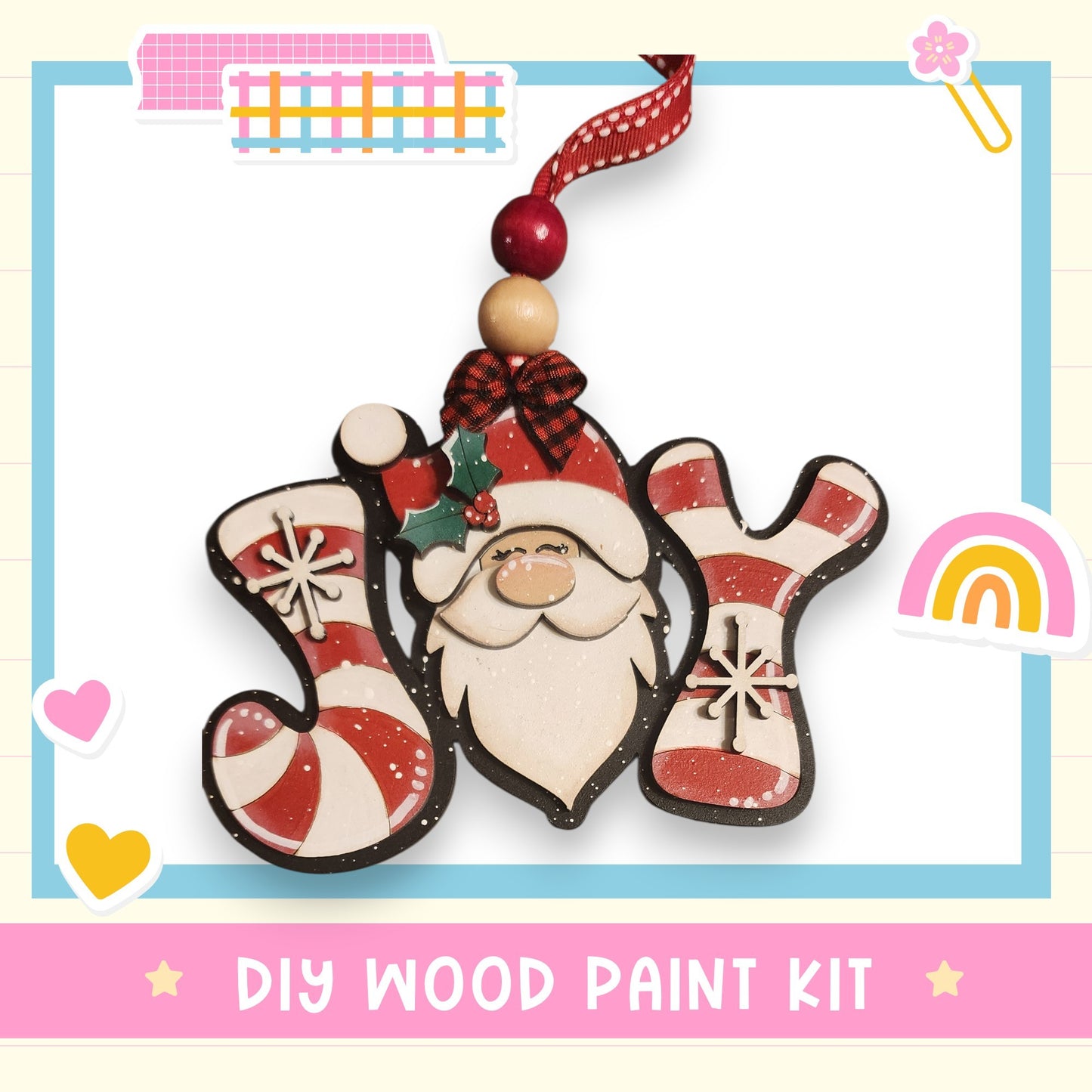 a DIY wood paint kit for creating a wooden ornament in the shape of the word "Joy". The ornament is designed to resemble a smiling Santa Claus figure, complete with a red and white striped hat and candy cane. The kit includes the necessary materials and instructions for creating this festive ornament.