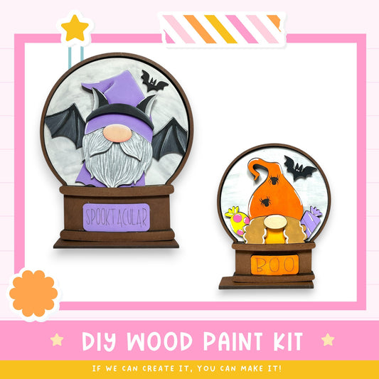 two wooden paint kits, one labeled "SPOOCTACULAR" and the other "BOO", both shaped like gnomes. The kits appear to be designed for creating custom wooden decorations or Halloween-themed items.