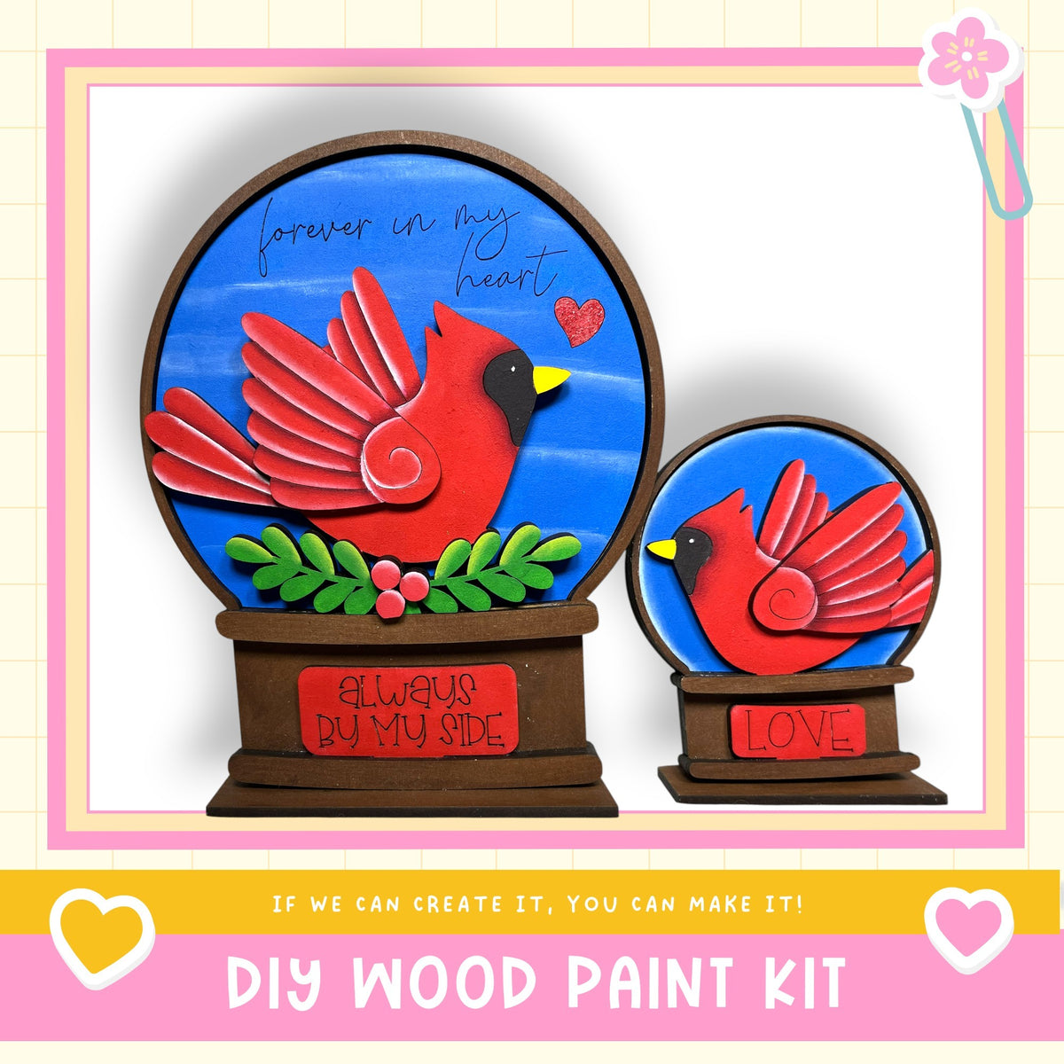 two wooden snow globes, each depicting a red cardinal bird. The snow globes are set against a blue background, and there is a message that reads "Forever in my heart" written on them. The image also includes a DIY wood paint kit, suggesting that the viewer can create their own snow globes.