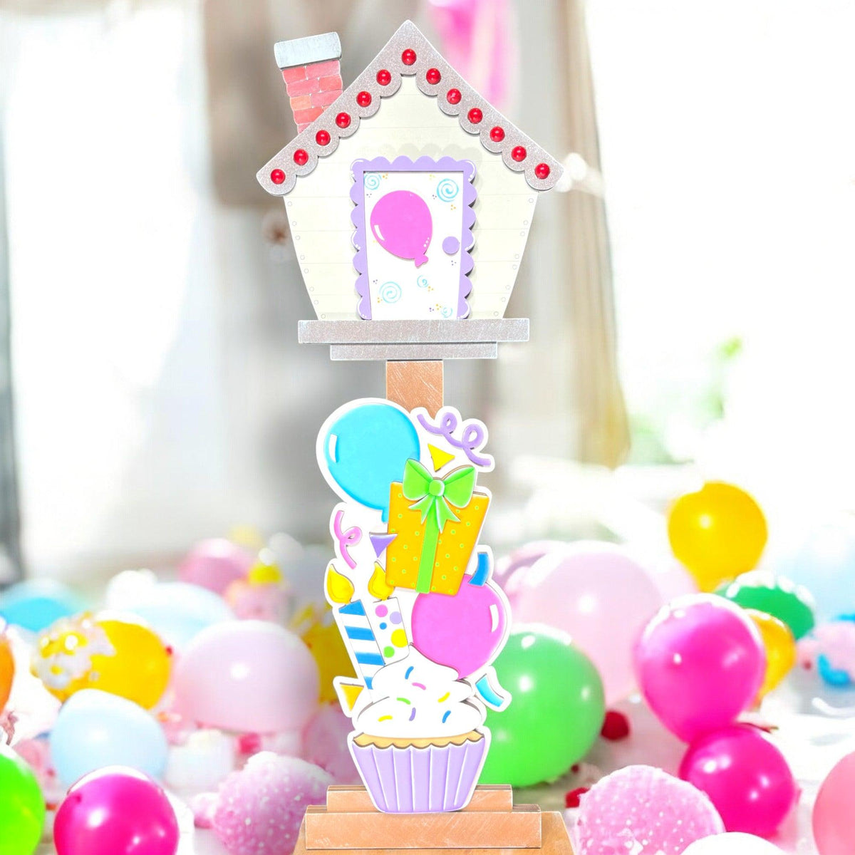 a cupcake with a house on top surrounded by balloons