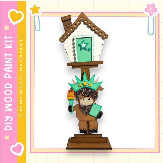 A wooden figurine of a cartoon character, resembling a small animal or a fairy, is standing on a platform and holding a book. The background of the image is white, and there are decorative elements such as hearts and stars around the scene.